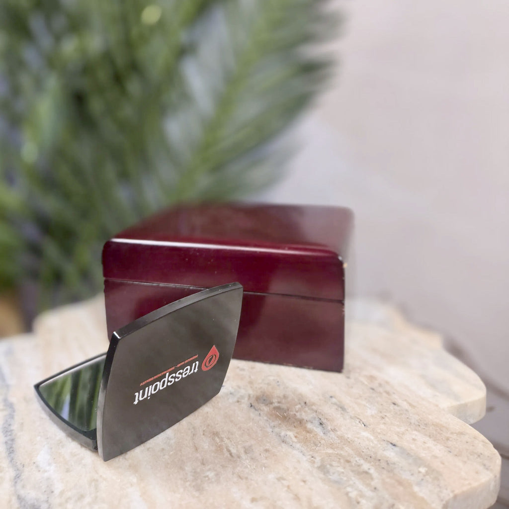 Tresspoint compact folding mirror open on a stone table, showing the mirrored panel and the Tresspoint logo