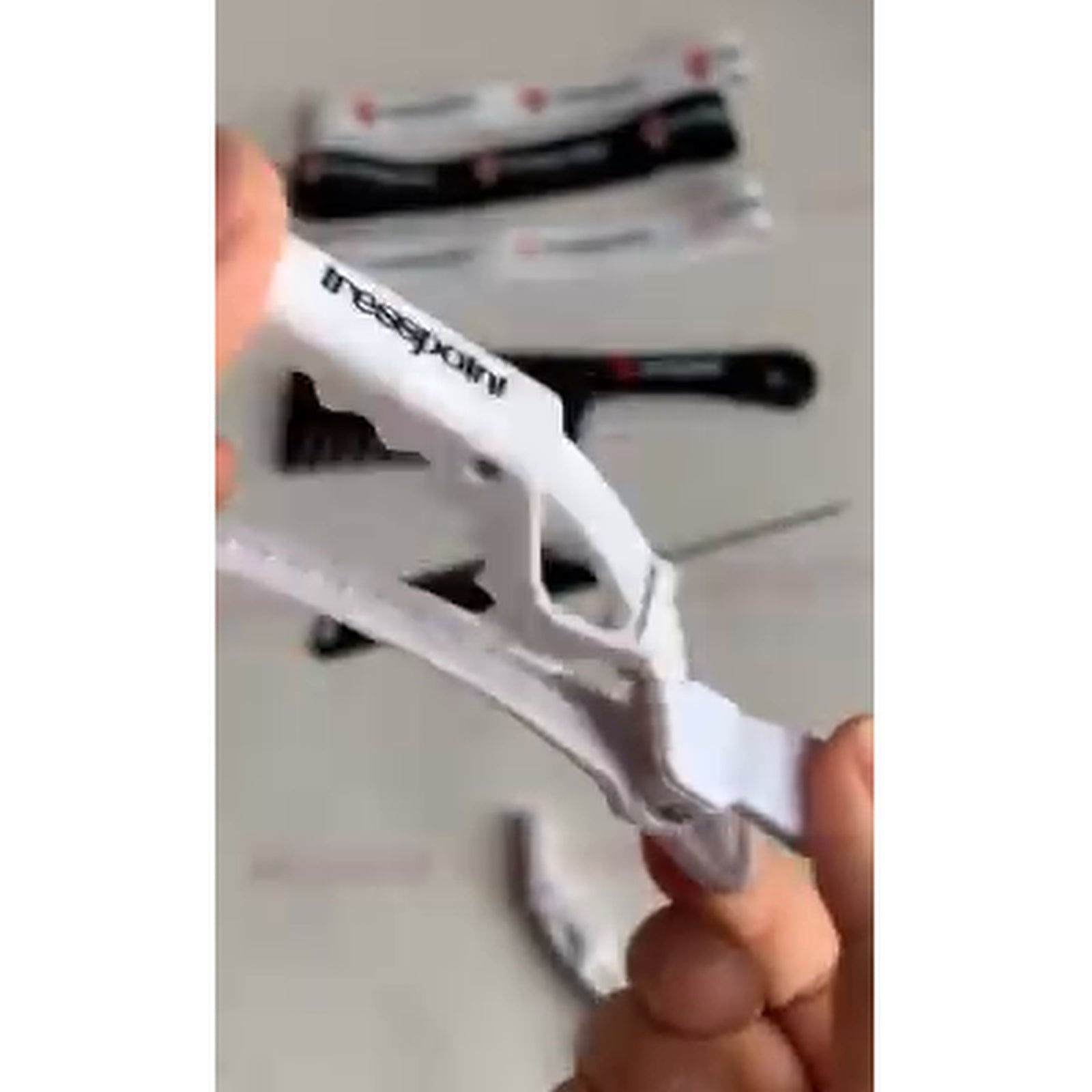 Tresspoint crease-free sectioning clip in white, held open to show the grip jaw for parting thick textured hair